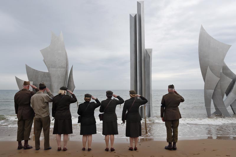 Enthusiasts of England salute in front of The Brave, a monument dedicated to the American soldiers who landed on Omaha Beach on D-Day, in Saint-Laurent-sur-Mer, Tuesday, June 4, 2019, in Normandy. Photo: AP.