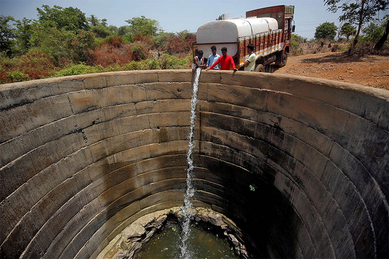 FILE PHOTO: A dried-up well is refilled with water from a water tanker in Thane district in the western state of Maharashtra, India, May 30, 2019. Photo: Reuters