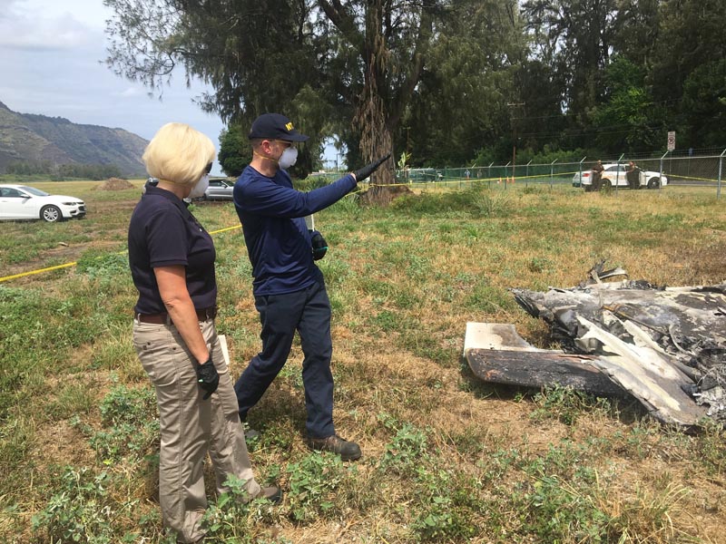 NTSB investigator Eliott Simpson briefing NTSB Board Member Jennifer Homendy at the scene of the Hawaii skydiving crash in Oahu, Hawaii, Sunday, June 23, 2019. No one aboard survived the crash, which left a small pile of smoky wreckage near the chain link fence surrounding Dillingham Airfield about an hour north of Honolulu. Photo: National Transportation Safety Board via AP