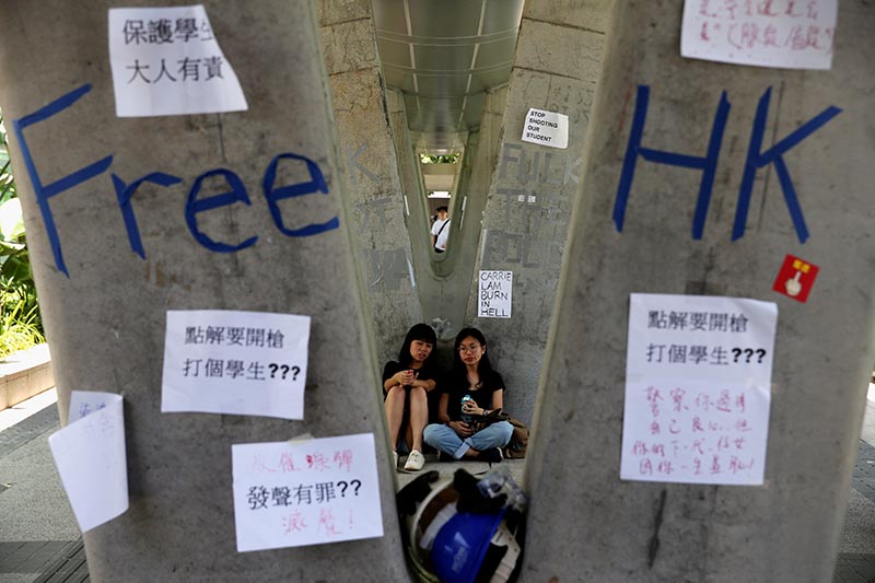 People sit next to posters and signs placed following protests against the proposed extradition bill, in Hong Kong, China June 14, 2019. Photo: Reuters