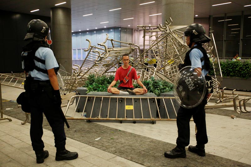 Police officers stand near a protester sitting during a protest to demand authorities scrap a proposed extradition bill with China, outside the Legislative Council in Hong Kong, China early June 10, 2019. Photo: Reuters