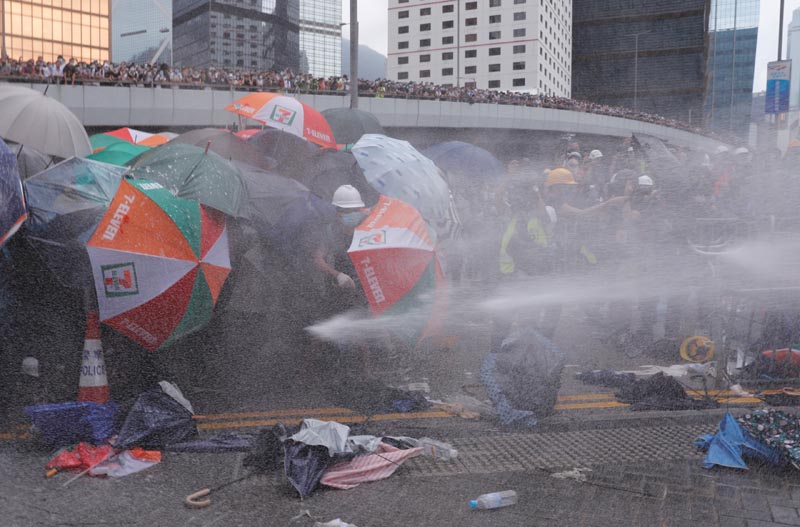Protesters are hit by police water cannon during a demonstration against a proposed extradition bill in Hong Kong, China June 12, 2019. Photo: Reuters