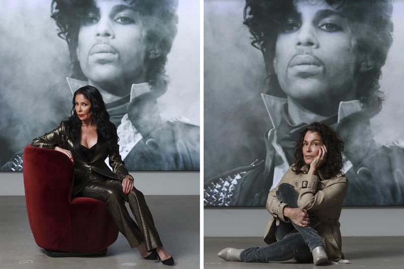 In this photo combination, singers Apollonia Kotero, left, and Susannah Melvoin pose in front of a photo of Prince at Warner Music Group in Los Angeles on Friday, May 31, 2019. Photo: AP