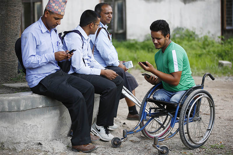 Ramesh Khatri, 21, a student with disability, looks at a mobile phone to check his SEE results, at Shree Khagendra New Life Special Education School, in Jorpati, Kathmandu, on Thursday, June 27, 2019. Photo: Skanda Gautam/THT