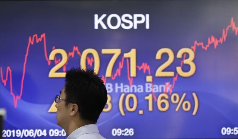 A currency trader walks by the screen showing the Korea Composite Stock Price Index (KOSPI) at the foreign exchange dealing room in Seoul, South Korea, Tuesday, June 4, 2019. Photo: AP.