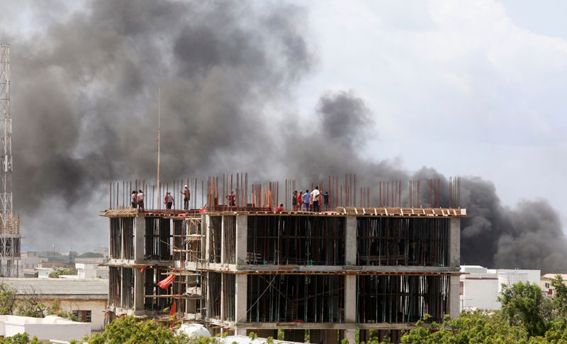 Workers are seen on a construction site as smoke billows from the scene of an explosion in Mogadishu, Somalia July 22, 2019. Photo: Reuters