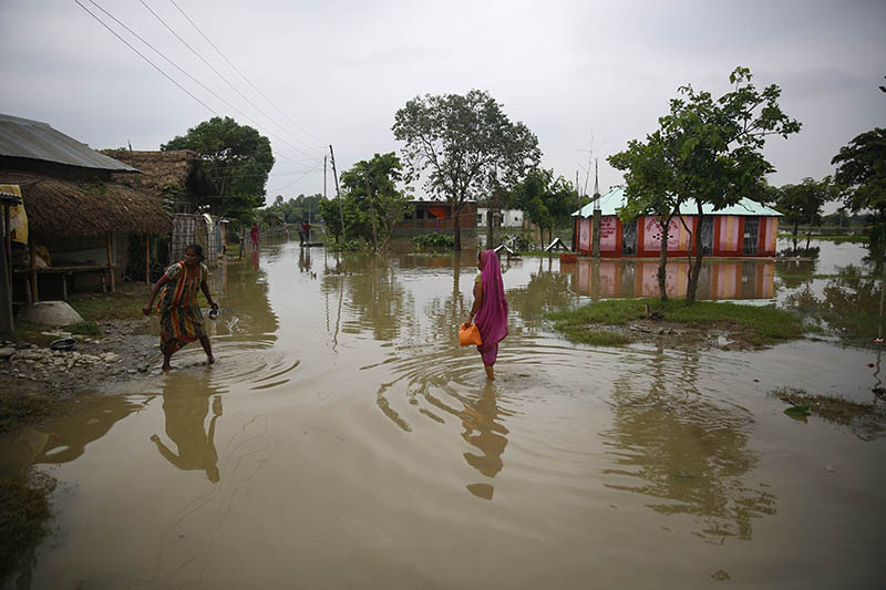 Women walks along a flooded road following heavy rainfall in Biratnagar, on Monday, July 15, 2019. Photo: Skanda Gautam/THT