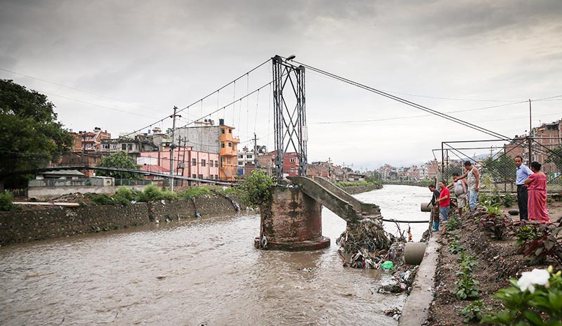 People looking at the bridge over the Bishnumati River in Kathmandu that was damaged due to Saturday nightu2019s heavy rainfall, on Sunday, July 7, 2019. The bridge connects Kankeshwori temple to Dallu.