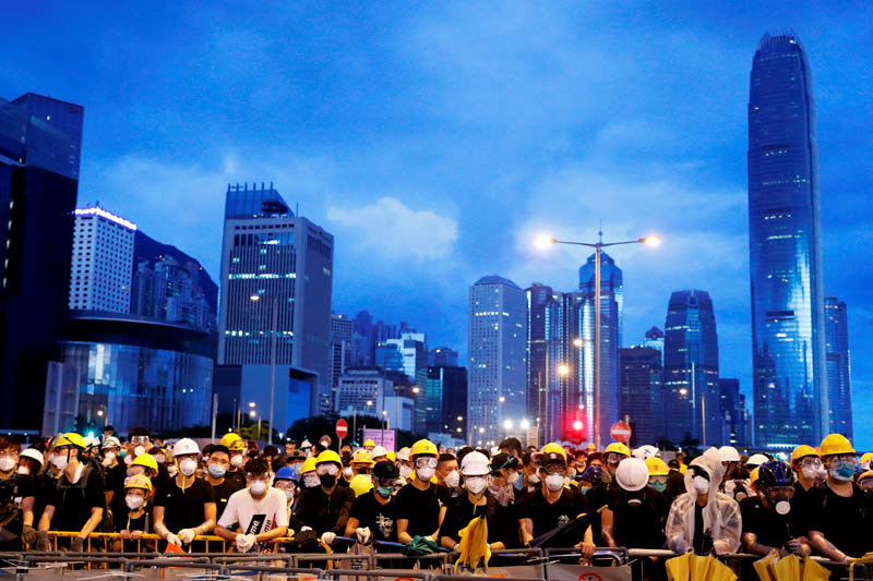 FILE PHOTO: Anti-extradition bill protesters stand behind a barricade during a demonstration near a flag raising ceremony for the anniversary of Hong Kong handover to China in Hong Kong, China July 1, 2019. Photo: Reuters