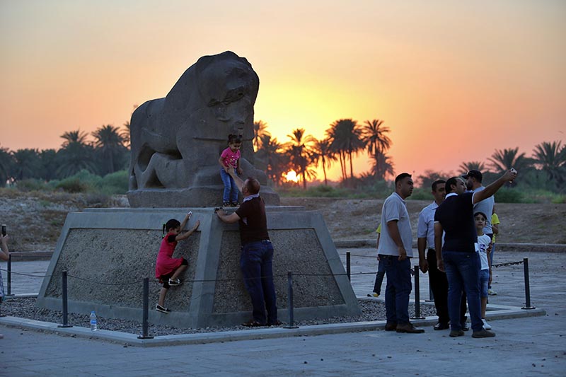 People stand near the Lion of Babylon at the archaeological site of Babylon, Iraq, Friday, July 5, 2019. Photo: AP