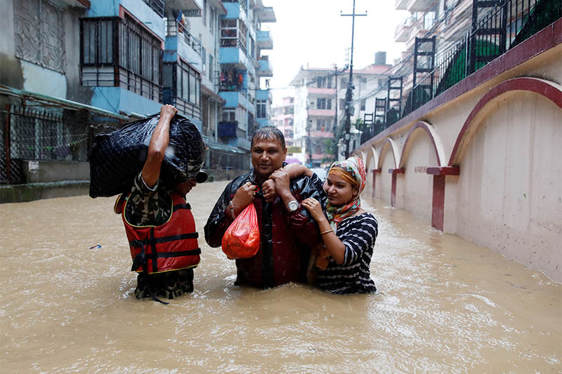 Residents walk towards dry ground from a flooded colony in Kathmandu, on Friday, July 12, 2019. Photo: Reuters
