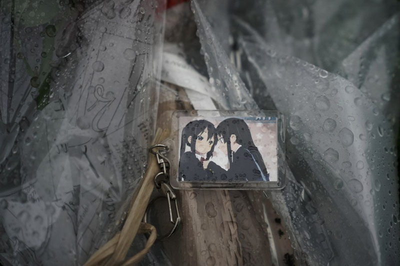 A keychain with a cartoon image is placed on top of flowers placed near the Kyoto Animation Studio building destroyed in an attack Friday, July 19, 2019, in Kyoto, Japan. Photo: AP