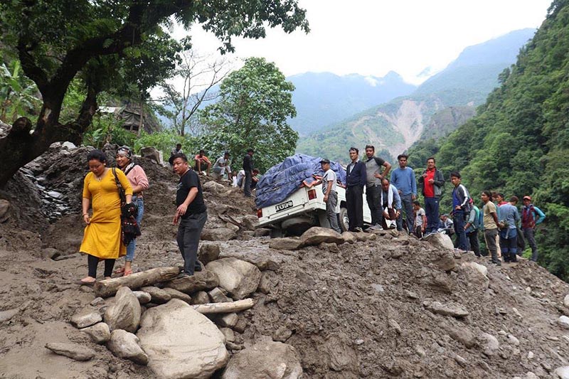 Stranded passengers negotiating their way after a mudslip obstructed the road in Khudi, Lamjung, on Thursday, July 11, 2019. Photo: THT