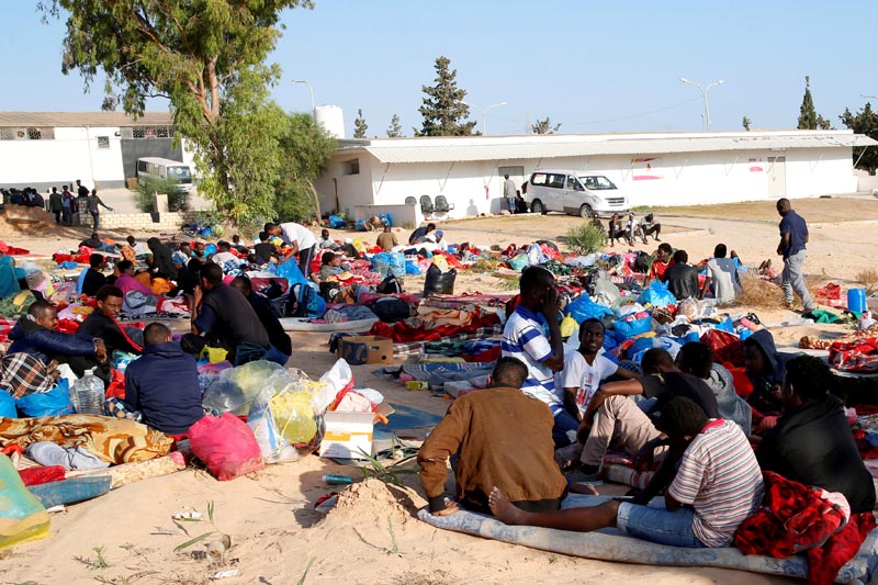 FILE PHOTO: Migrants are seen with their belongings in the yard of a detention centre for mainly African migrants, hit by an air strike, in the Tajoura suburb of Tripoli, Libya July 3, 2019. Photo: Reueters