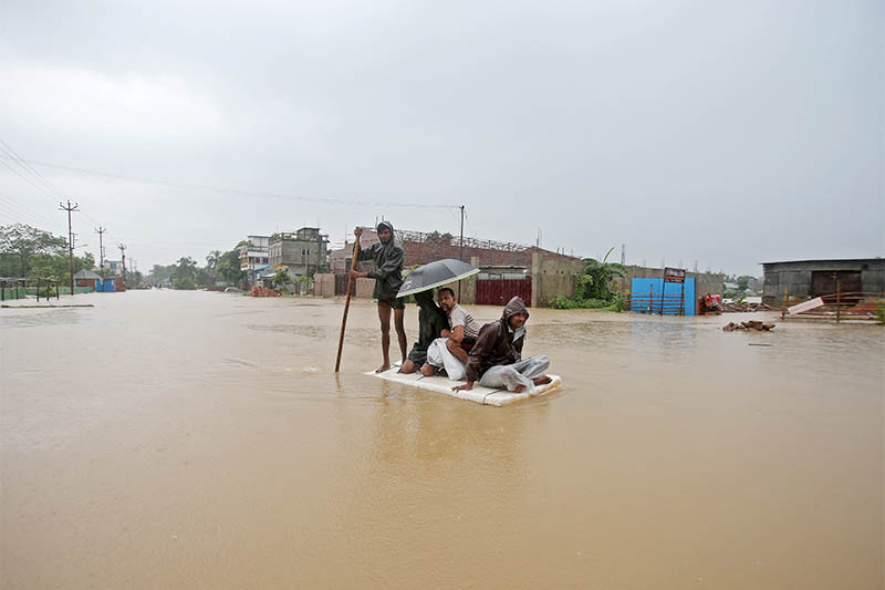 Villagers use a makeshift raft to cross a flooded area on the outskirts of Agartala, India, on Monday, July 15, 2019. Photo: Reuters