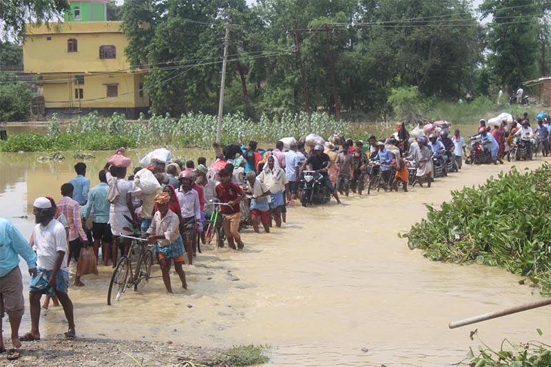 Commuters walking on an inundated street as they head towards the bus park in Gaur Municipality of Rautahat district, on Monday, July 15, 2019. Photo: THT