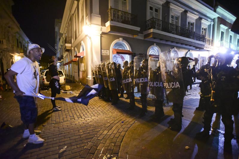 Demonstrators stand in front of riot control units during clashes in San Juan, Puerto Rico, Monday, July 22, 2019. Photo: AP