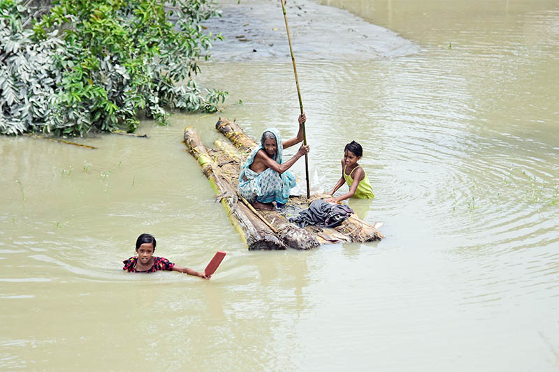A woman rows a makeshift raft as girls wade through flood waters at the Laharighat village in Morigaon district, in the northeastern state of Assam, India, on Sunday, July 21, 2019. Photo: Reuters