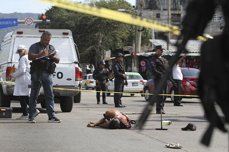 The body of a bloodied man lies in the middle of a street where police and forensic workers secure the crime scene in Acapulco, Mexico. File Photo: AP
