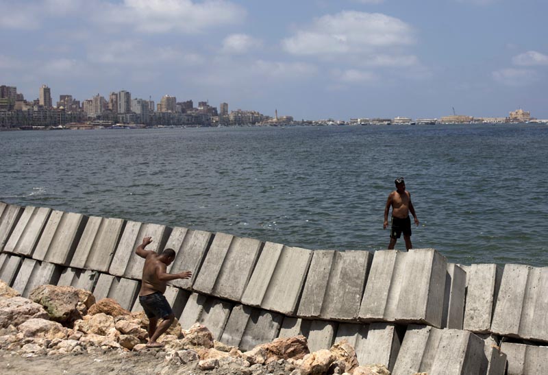 In this August 8, 2019, photo, workers prepare to place cement blocks to reinforce the sea wall against rising water levels on the corniche in Alexandria, Egypt. Photo: AP