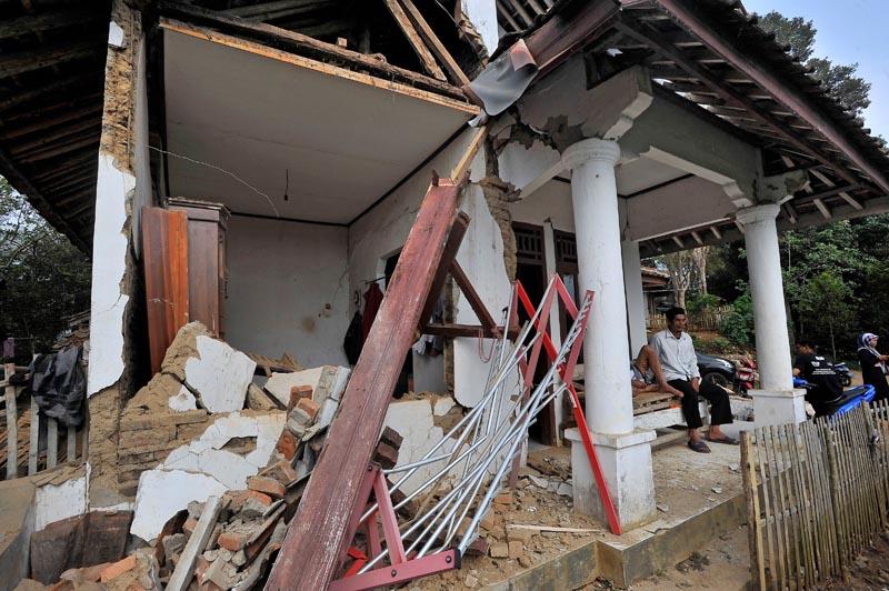 Locals sit at thier house damaged after an earthquake hit in Pandeglang, Banten province, Indonesia, August 3, 2019. Photo: Antara Foto/Asep Fathulrahman/ via Reuters