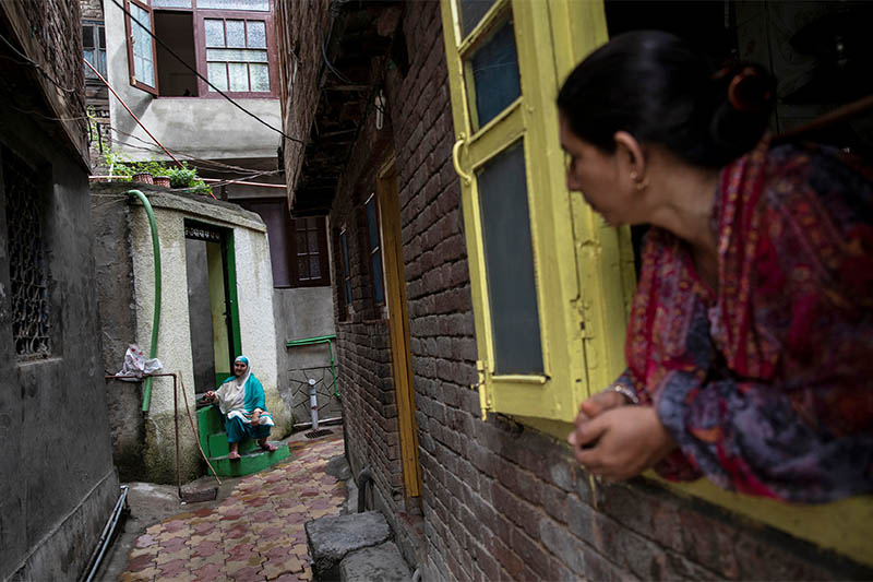 A Kashmiri woman talks to another in an alley during restrictions after the scrapping of the special constitutional status for Kashmir by the government, in Srinagar, August 14, 2019. Photo: Reuters