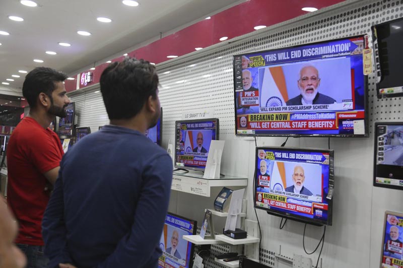 Indians watch Prime Minister Narendra Modi address the nation in a televised speech, in an electronics store in Jammu, India, Thursday, August 8, 2019. Photo: AP