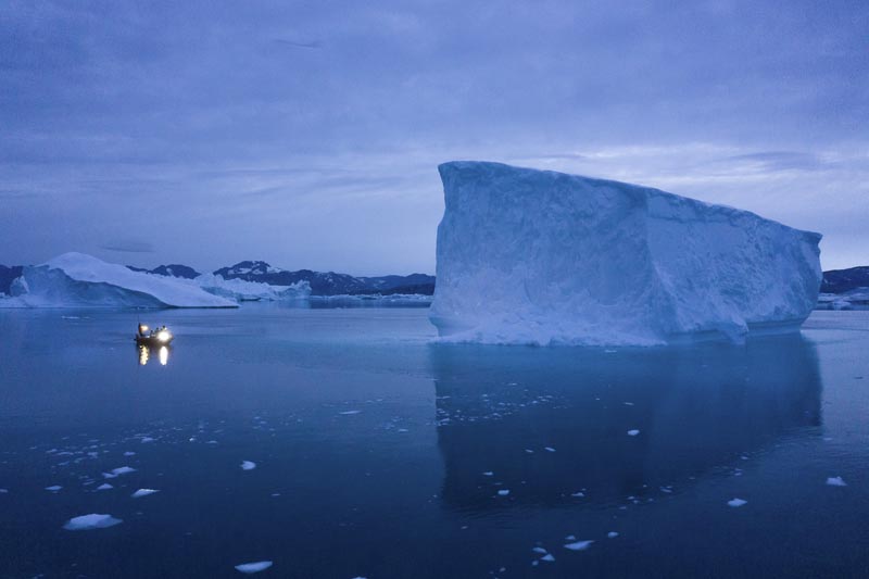 FILE - In this August 15, 2019, file photo, a boat navigates at night next to large icebergs in eastern Greenland. Photo: AP