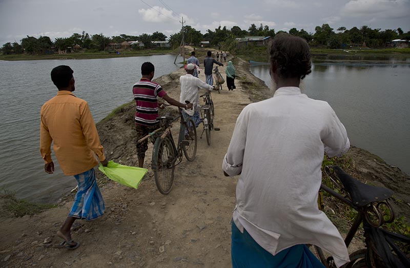 Villagers walk on an embankment on their way to check names in the final list of the National Register of Citizens (NRC) at an NRC center in Pabhokati village in Morigaon district, in the northeastern Indian state of Assam on August 31, 2019. Photo: AP