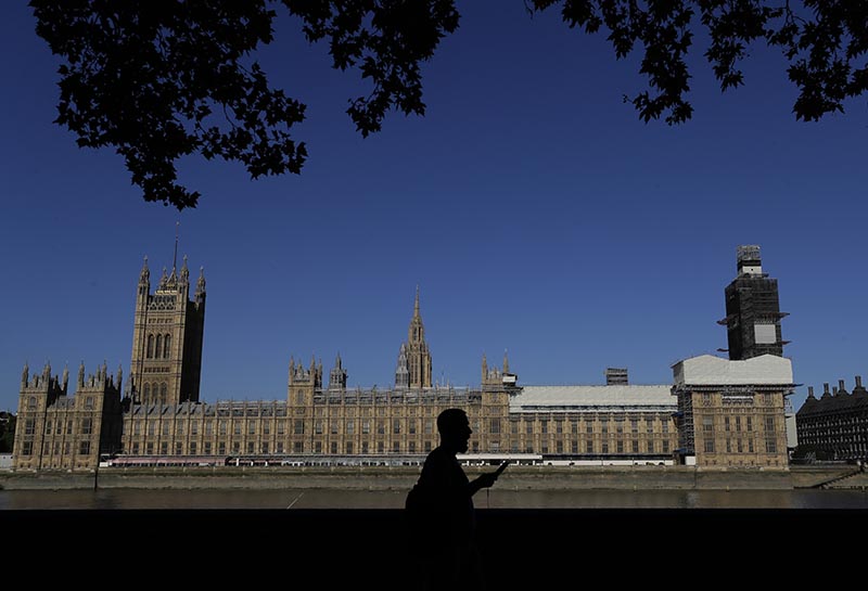 A pedestrian passes Britain's Houses of Parliament on the bank of The River Thames in London on August 31, 2019. Photo: AP