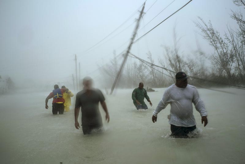 Volunteers walk under the wind and rain from Hurricane Dorian through a flooded road as they work to rescue families near the Causarina bridge in Freeport, Grand Bahama, Bahamas, Tuesday, September 3, 2019. Photo: AP