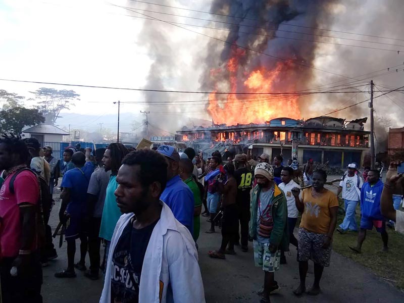 People gather as shops burn in the background during a protest in Wamena in Papua province, Indonesia, Monday, September 23, 2019. Photo: AP