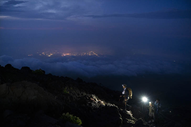 Climbers make their way along the Yoshida trail toward the summit of Mount Fuji as the glow from the town's lights are visible through clouds Friday, August 2, 2019, in Japan. Photo: AP