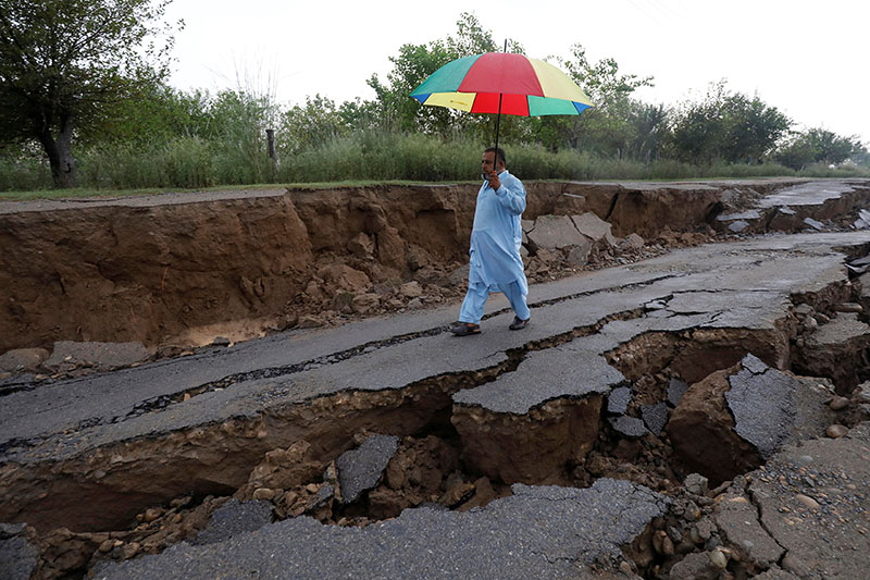 A man walks with an umbrella along a damaged road after an earthquake in Jatlan, Mirpur, Pakistan September 25, 2019. Photo: Reuters