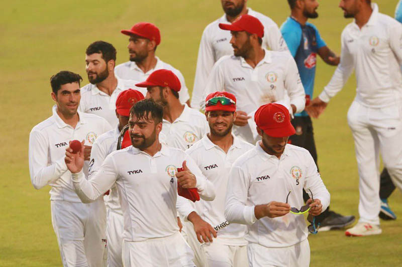 Afghanistan's skipper Rashid Khan holds a match ball as he walks off the ground along with other players after beating Bangladesh in a test match. Courtesy: Rashid/Twitter