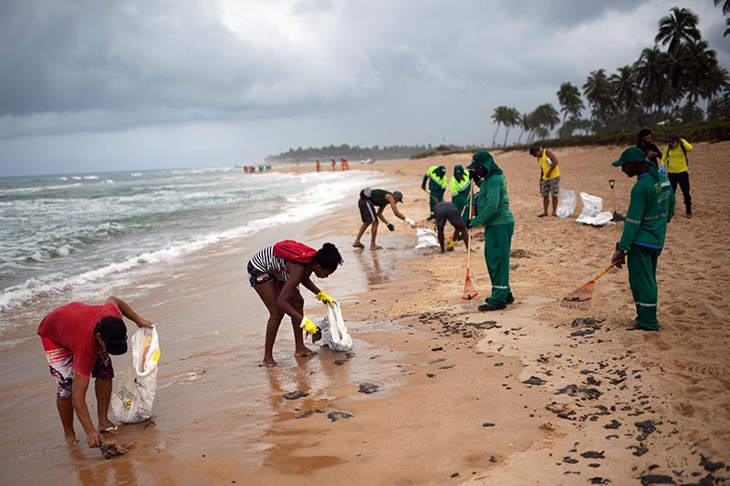 Municipal employees and residents work to remove an oil spill on Barra de Jacuipe beach in Camacari, Bahia state, Brazil October 22, 2019. Photo: Reuters