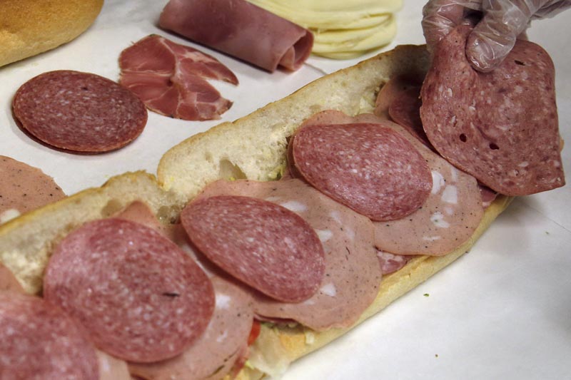 A man makes a submarine sandwich with mortadella, cooked salami, ham, Genoa salami and sweet capicola at a delicatessen in Massachusetts, June 5, 2014. Photo: AP/File