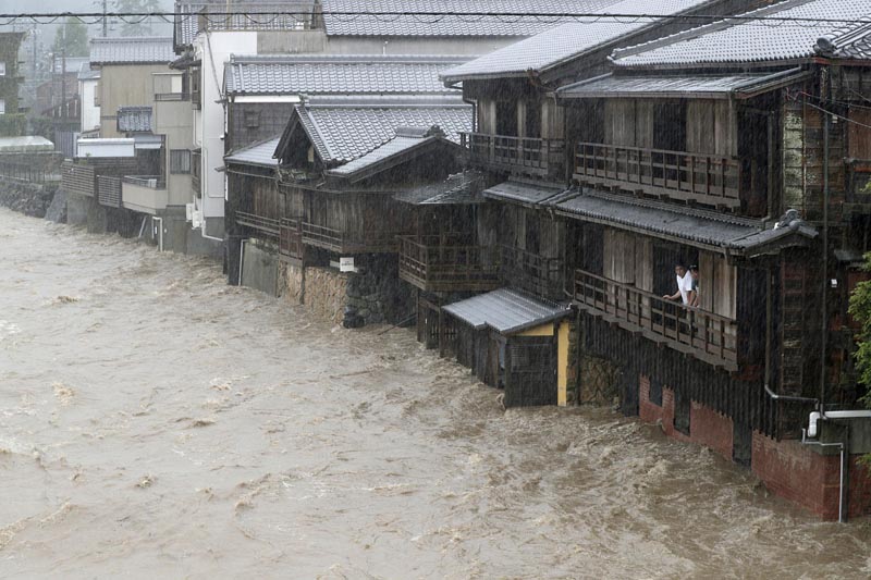 Men watch the swollen Isuzu River due to heavy rain caused by Typhoon Hagibis in Ise, central Japan, October 12, 2019.  Photo: Kyodo via Reuters
