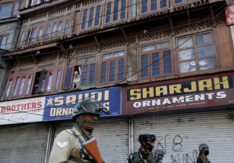 A Kashmiri man looks out from a window as Indian security forces stand at the site of a grenade attack in Srinagar October 12, 2019. Photo: Reuters