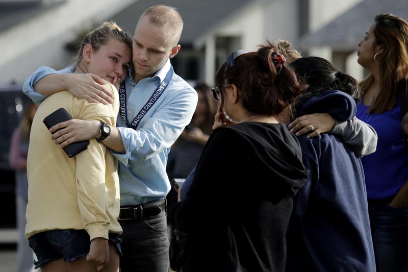 DJ Hamburger, centre in blue, a teacher at Saugus High School, comforts a student after reports of a shooting at the school on Thursday, November 14, 2019, in Santa Clarita, California. Photo: AP