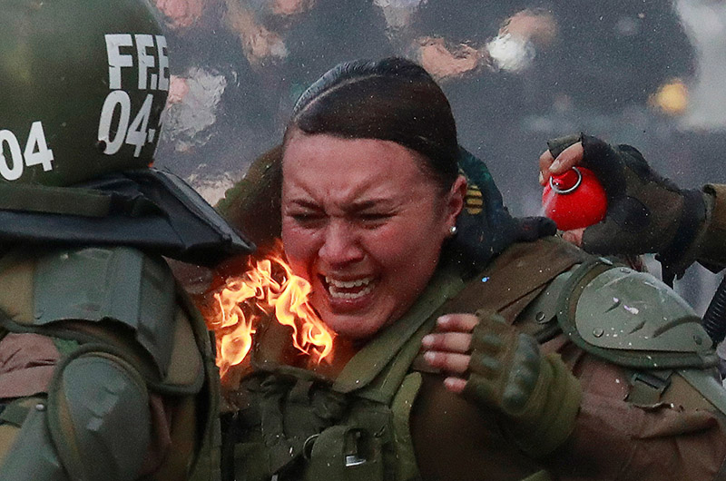 A riot police officer on fire is assisted by colleagues during a protest against Chile's government in Santiago, Chile, on November 4, 2019. Photo: Reuters