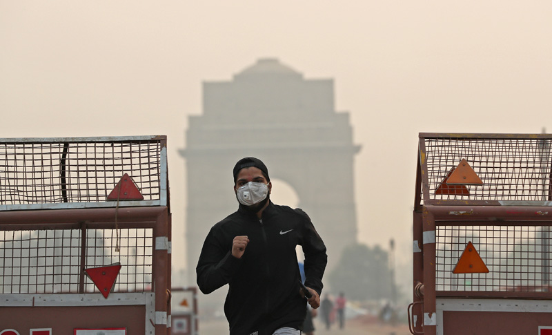 A man wearing a mask runs past the India Gate on a smoggy morning in New Delhi, India, October 28, 2019. Photo: Reuters