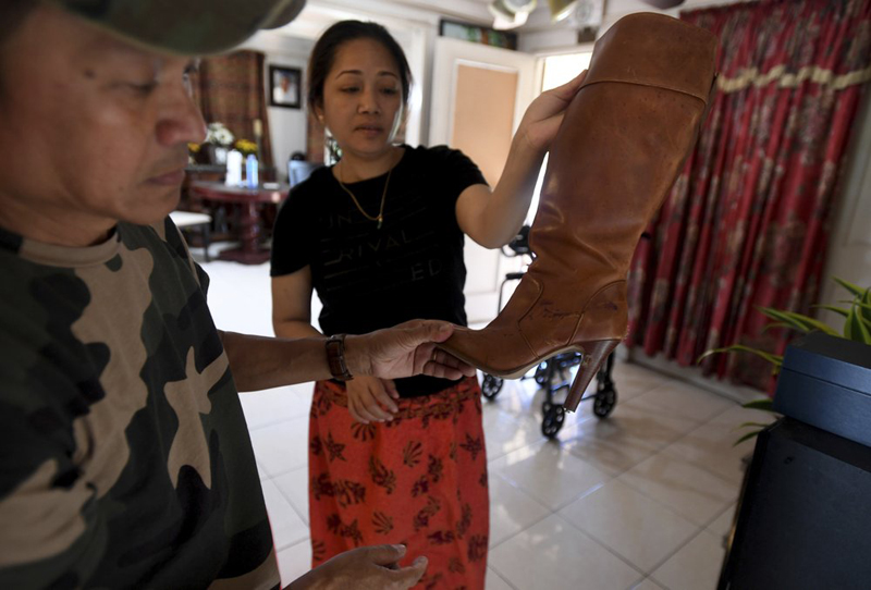 Chanchenda Hou, and Da Heng, hold up a victims' boot with bullet holes in it after the Halloween themed birthday party hosted at their home ended with 3 dead and 9 injured. Photo: AP