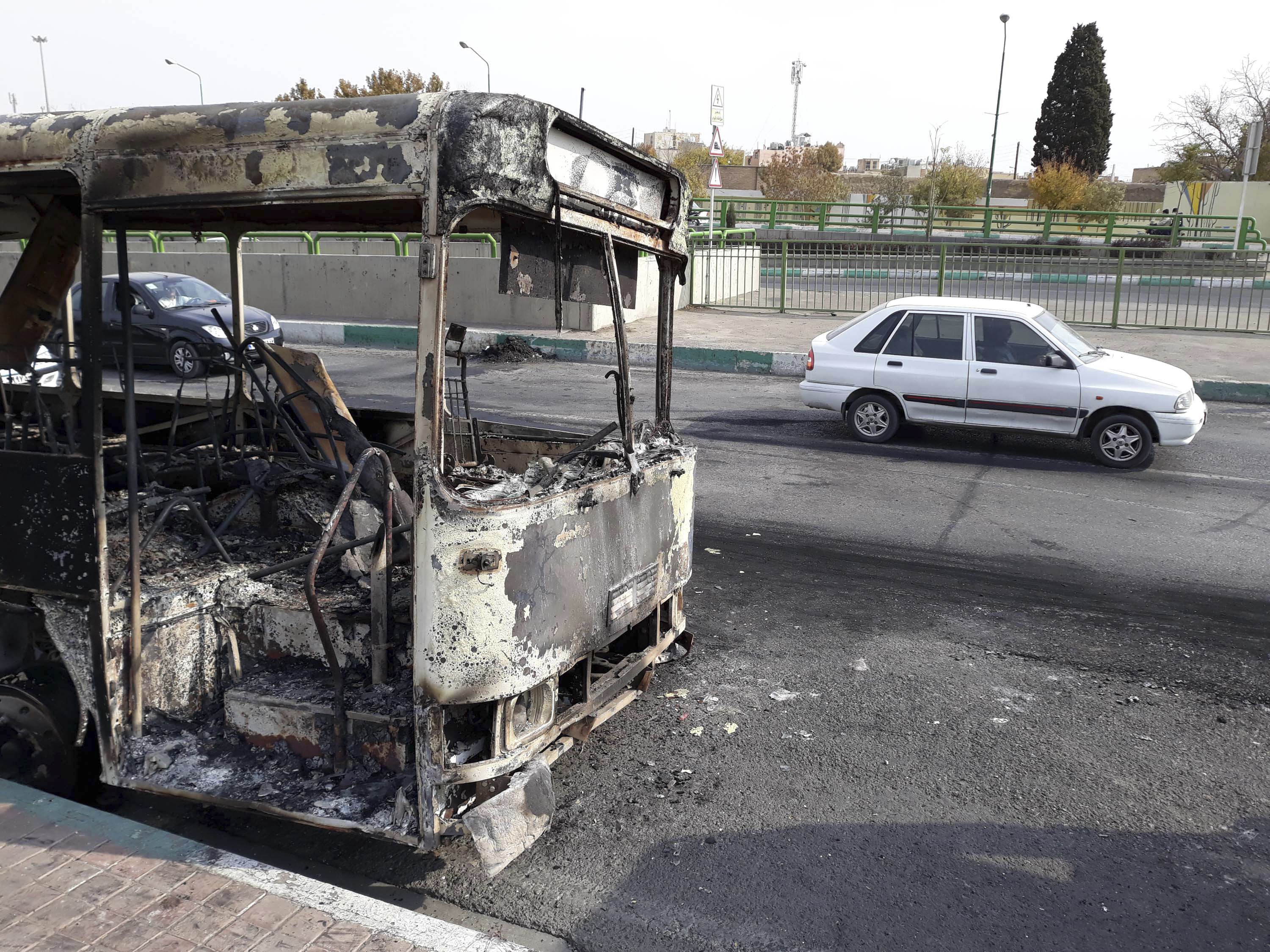 This photo released by the Iranian Students' News Agency, ISNA, shows cars drive past a scorched public bus that remained on the street after protests that followed authorities' decision to raise gasoline prices, in Tehran, Iran, Sunday, November 17, 2019. Photo: Morteza Zangane/ISNA via AP
