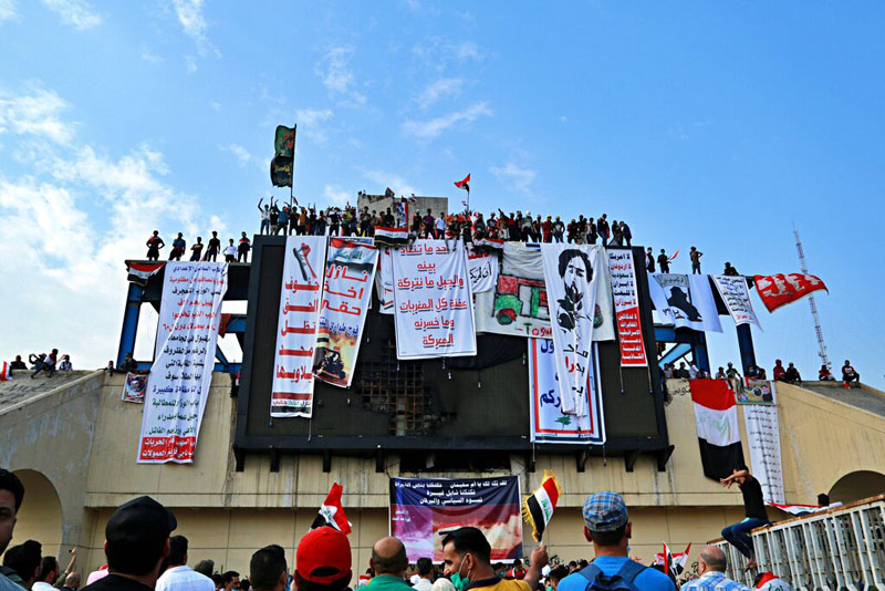In this October 30, 2019, photo, Iraqi anti-government protesters hang their demands and slogans while standing on a building near Tahrir Square, Baghdad, Iraq. Photo: AP