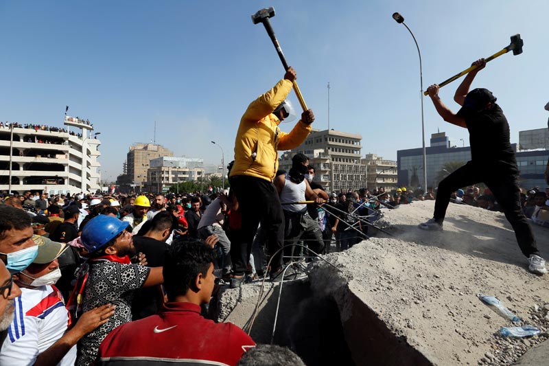 Iraqi demonstrators smash concrete walls at Sinak Bridge during the ongoing anti-government protests, in Baghdad, Iraq November 16, 2019. Photo: Reuters