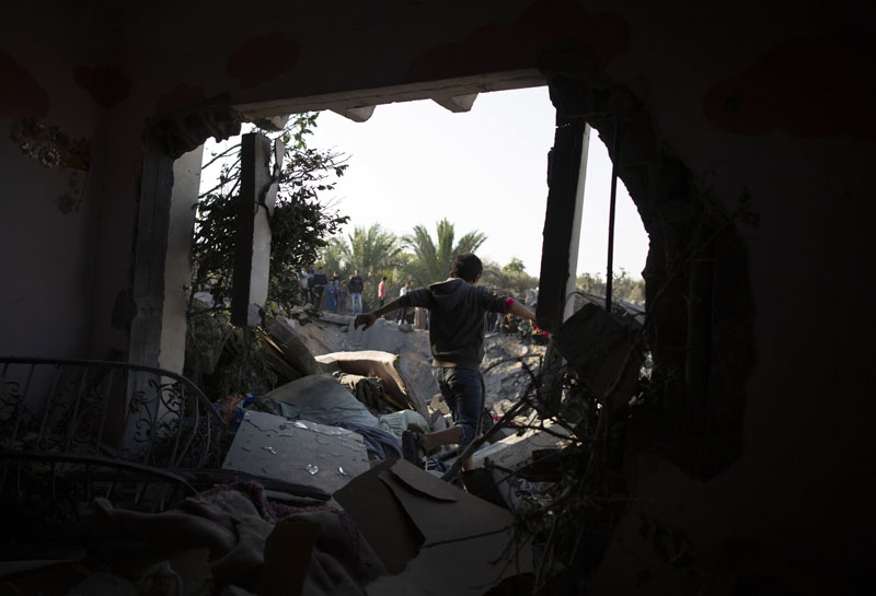 A Palestinian boy walks through a hole in a wall of a destroyed house following overnight Israeli missile strikes, in the town of Khan Younis, southern Gaza Strip, Thursday, Nov 14, 2019. Photo: AP