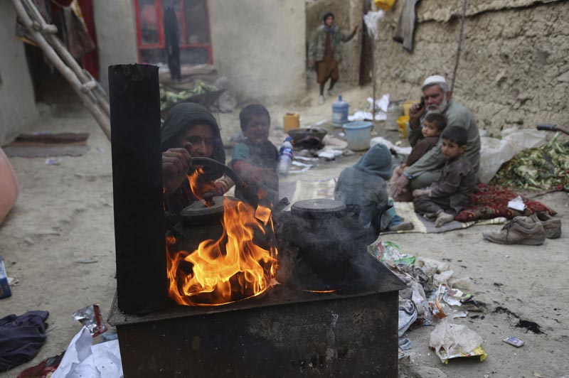 In this October 29, 2019 photo, Yousuf, who fled with his family from his home in eastern Afghanistan eight years ago to escape the war, sits with children while his wife burns plastic as she makes tea, in Kabul, Afghanistan. Photo: AP