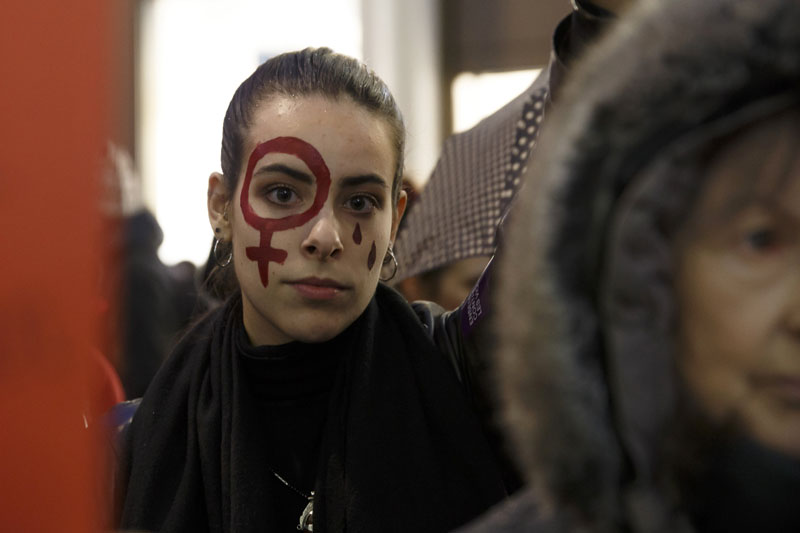 A woman wearing the female gender symbol on her face demonstrates around a symbolic circle of shoes and candles, during a rally against violence towards women on International Day for the Elimination of Violence against Women, in Geneva, Switzerland, Monday, Nov. 25, 2019. Photo: AP