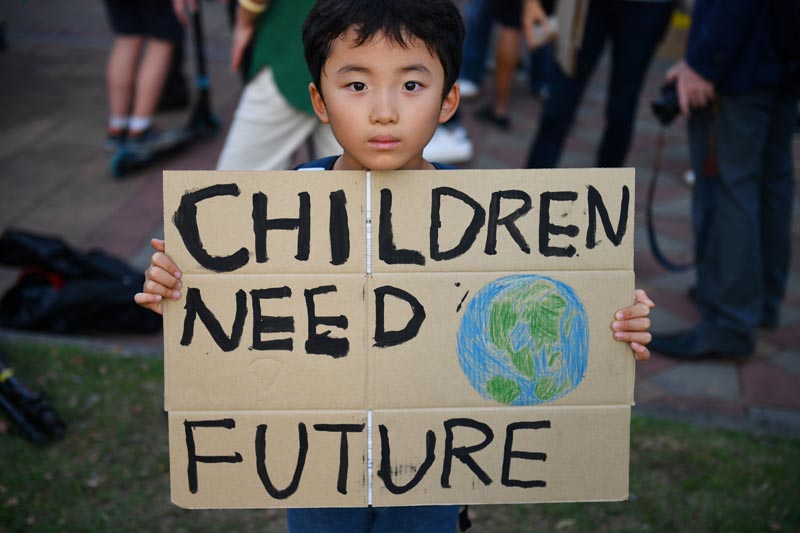 A child holds a placard during a 'drop dead' flashmob protest against climate change consequences at Lumpini Park in Bangkok, Thailand November 29, 2019. Photo: Reuters